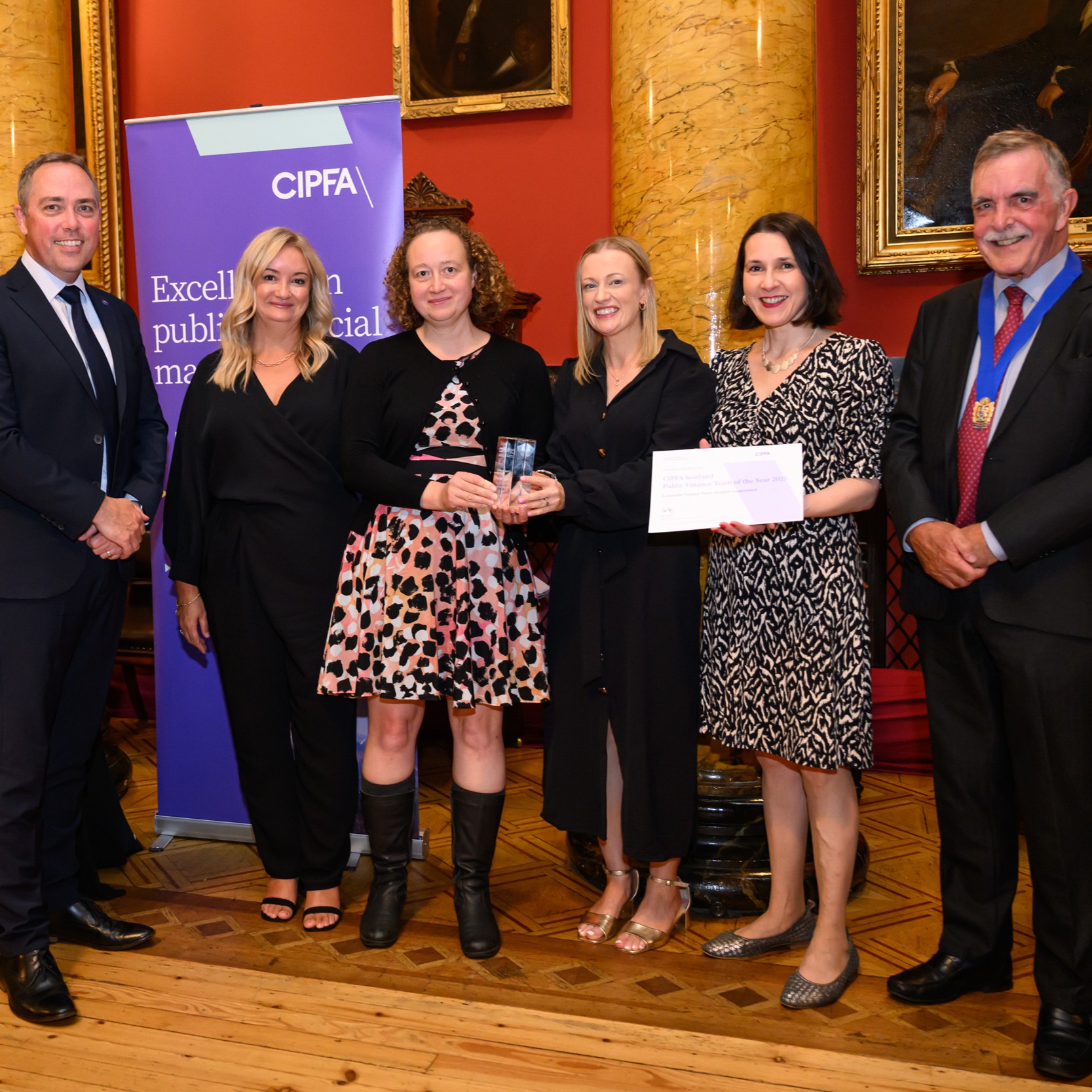 Group of smartly dressed people holding a certificate 